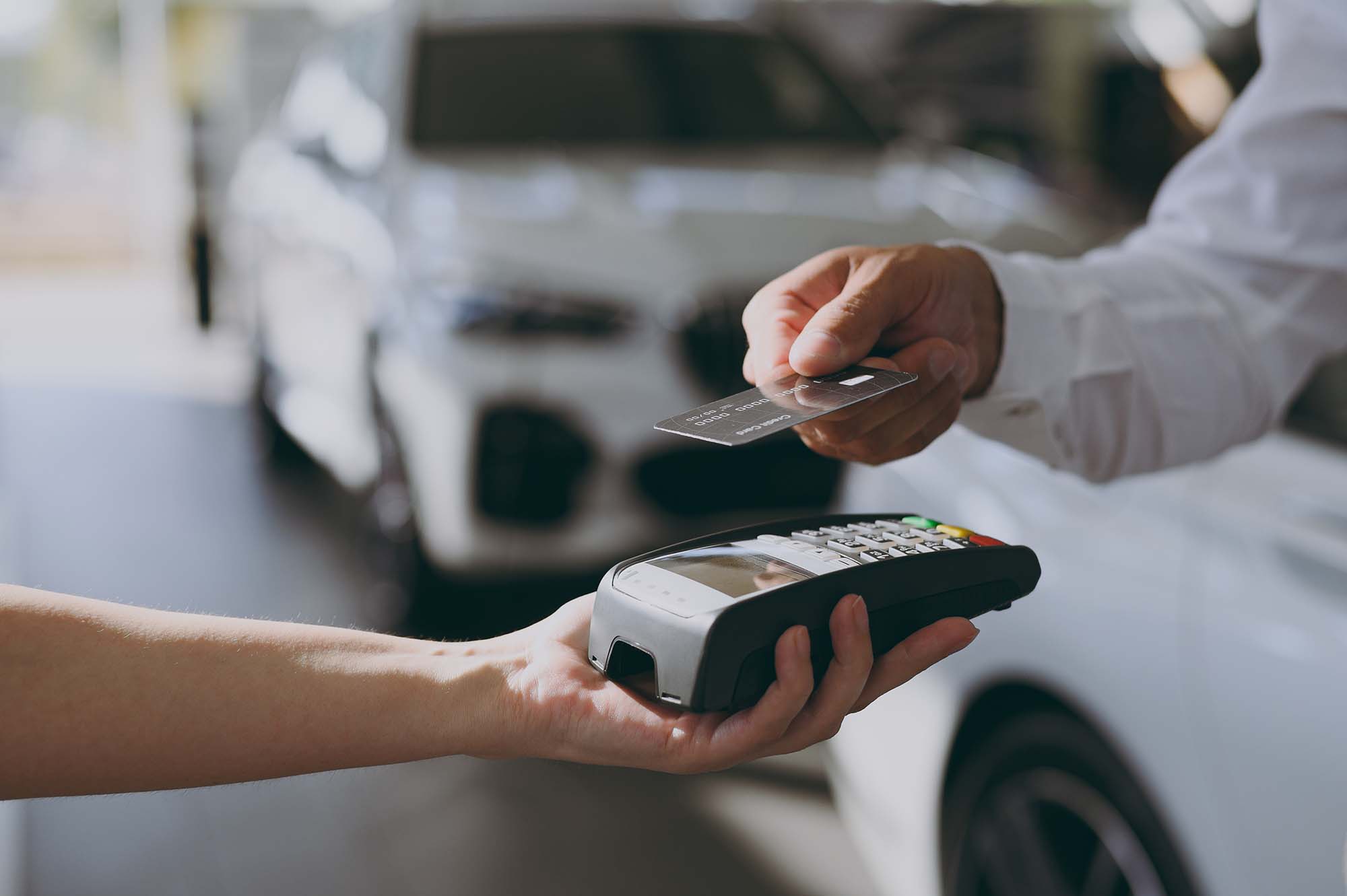 Person holding a credit card near a payment terminal for a contactless transaction.